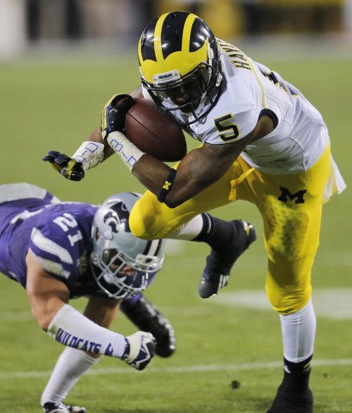 Michigan RB Justice Hayes rushes past Kansas State’s Jonathan Truman in the Wildcats’ 31-17 win in the Buffalo Wild Wings Bowl Saturday in Tempe. (Credit: AP)