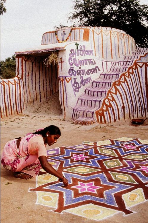 A woman painting a kolam in Tamil Nadu, India. A kolam is a form of sandpainting that is drawn using rice powder by female members of the family in front of their home.