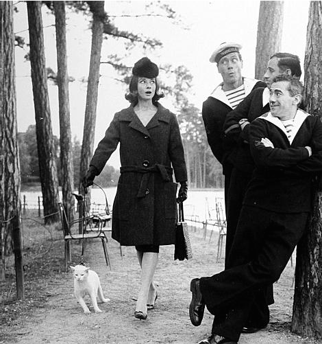 Audrey Hepburn walks a cat as Sailors look on c1959