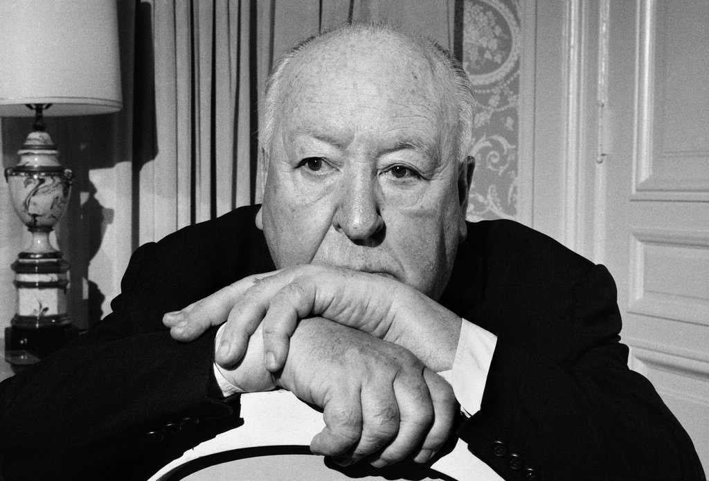 April 1, 1976: Alfred Hitchcock in his suite at the St. Regis Hotel in New York. “After knighthood,” the caption read, quoting Hitchcock, ” ‘all that was left was to await death, a few vodkas hastening its advent.’ ” A note on the back of the photograph clarified who was directing the photo shoot: “The picture showing Mr. Hitchcock creeping his way through the plant in his room was his idea.” Hitchcock died the following year. Photo: Jack Manning/The New York Times 
