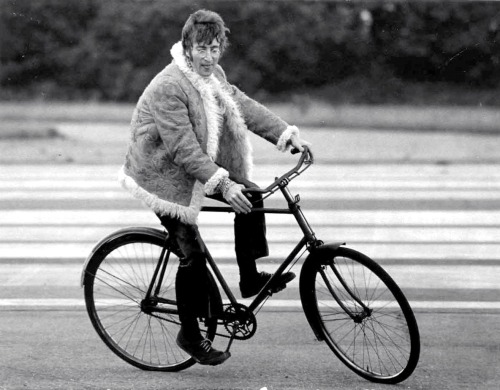 John Lennon rides a bike.