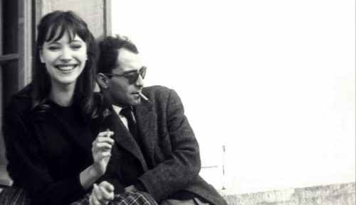 

criterioncorner:
THIS IS THE STORY OF HOW ANNA KARINA & JEAN-LUC GODARD FIRST “GOT TOGETHER”
Anna Karina: That happened while we were shooting the picture in Geneva. It was a strange love story from the beginning. I could see Jean-Luc was looking at me all the time, and I was looking at him too, all day long.  We were like animals. One night we were at this dinner in Lausanne. My boyfriend, who was a painter, was there too. And suddenly I felt something under the table – it was Jean-Luc’s hand. He gave me a piece of paper and then left to drive back to Geneva. I went into another room to see what he’d written.  It said, “I love you.  Rendezvous at midnight at the Café de la Prez.” And then my boyfriend came into the room and demanded to see the piece of paper, and he took my arm and grabbed it and read it.  He said, “You’re not going.” And I said, “I am.” And he said, “But you can’t do this to me.”  I said, “But I’m in love too, so I’m going.” But he still didn’t believe me. We drove back to Geneva and I started to pack my tiny suitcase.  He said, “Tell me you’re not going.” And I said, “I’ve been in love with him since I saw him the second time. And I can’t do anything about it.” It was like something electric. I walked there, and I remember my painter was running after me crying. I was, like, hypnotized – it never happened again to me in my life.
So I get to the Cafe de la Prez, and Jean-Luc was sitting there reading a paper, but I don’t think he was really reading it. I just stood there in front of him for what seemed like an hour but I guess was not more that thirty seconds. Suddenly he stopped reading and said,” Here you are. Shall we go?” So we went to his hotel. The next morning when I woke up he wasn’t there. I got very worried. I took a shower, and then he came back about an hour later with the dress I wore in the film - the white dress with flowers. And it was my size, perfect. It was like my wedding dress.
We carried on shooting the film, and, of course, my painter left. When the picture was finished, I went back to Paris with Jean-Luc, Michel Subor, who was the main actor, and Laszlo Szabo, who was also in the film, in Jean-Luc’s American car. We were all wearing dark glasses and we got stopped at the border – I guess they thought we were gangsters. When we arrived in Paris, Jean-Luc dropped the other two off and said to me, “Where are you going?”  I said, “I have to stay with you. You’re the only person I have in the world now.” And he said, “Oh my God.”
Extract taken from an interview with Anna Karina conducted by Graham Fuller in Projections 13: Women Film-makers on Film-making, edited by Isabella Weibrecht, John Boorman and Walter Donohue (Faber & Faber, 2004) 
(via Focus Features)

