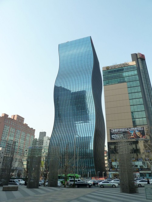 The GT Tower East with Fascinating ‘Rippling’ Glass Facade by ArchitectenConsort

ArchitectenConsort have completed the GT Tower East in Seoul, South Korea. With its elegantly undulating glass facade, the new high-rise brings a fascinating change to the angular architecture of the Korean capital. The form and positioning of the 130-metre-high building are the impressive result of the vision of architects Peter Couwenbergh and Edgar Bosman of ArchitectenConsort. They chose a uniform, glass finish for the facade, which has resulted in an organically pure form. The undulating motion of the facades provides an optically changing primary form when passing the building. Combined with the reflection of the light in the glass, this gives the building a special, iconic appearance. The dynamic appearance of GT Tower East is reinforced by the sight of the building, that seems to be dropping down below street level. As it were the building rises out of the Korean soil and then reaches upwards in a dancing movement, up into the infinity of the sky.

