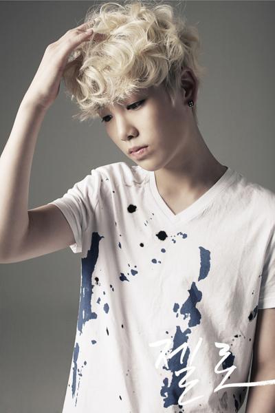 zelo from bap looking down at the ground in a sad manner while he touches his blonde, curly hair lightly